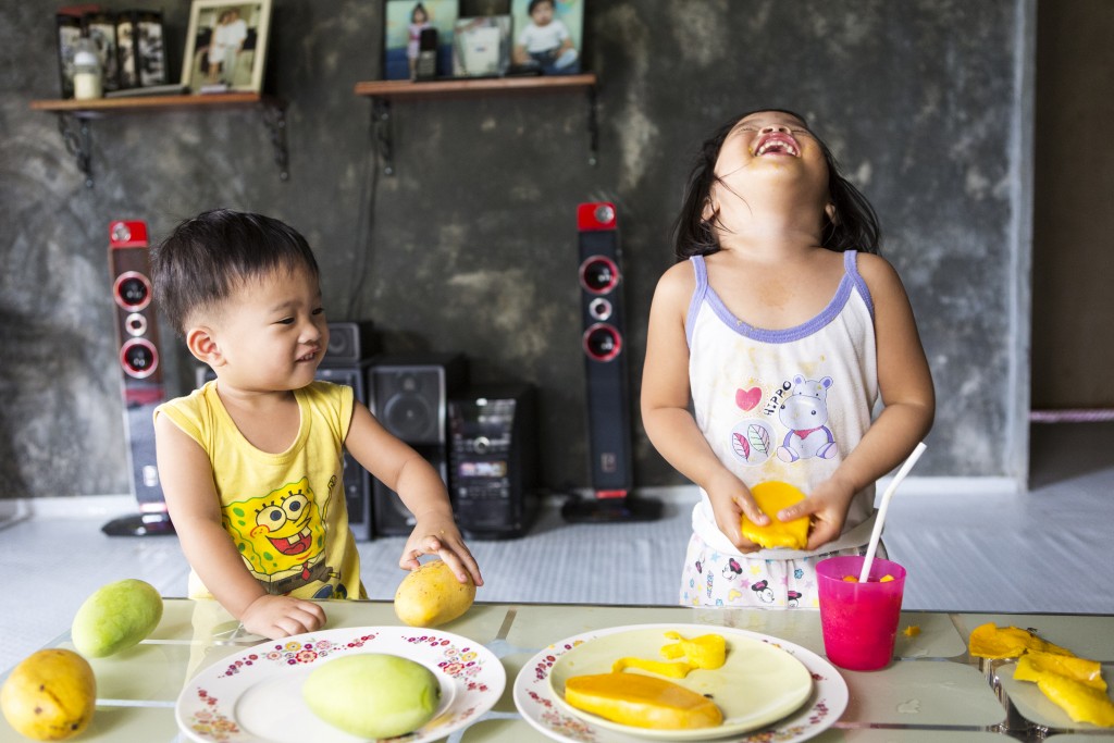 Lorraine, aged 2 and Liam, aged 1, eating mangos, Alix, Batangas City, Philippines.